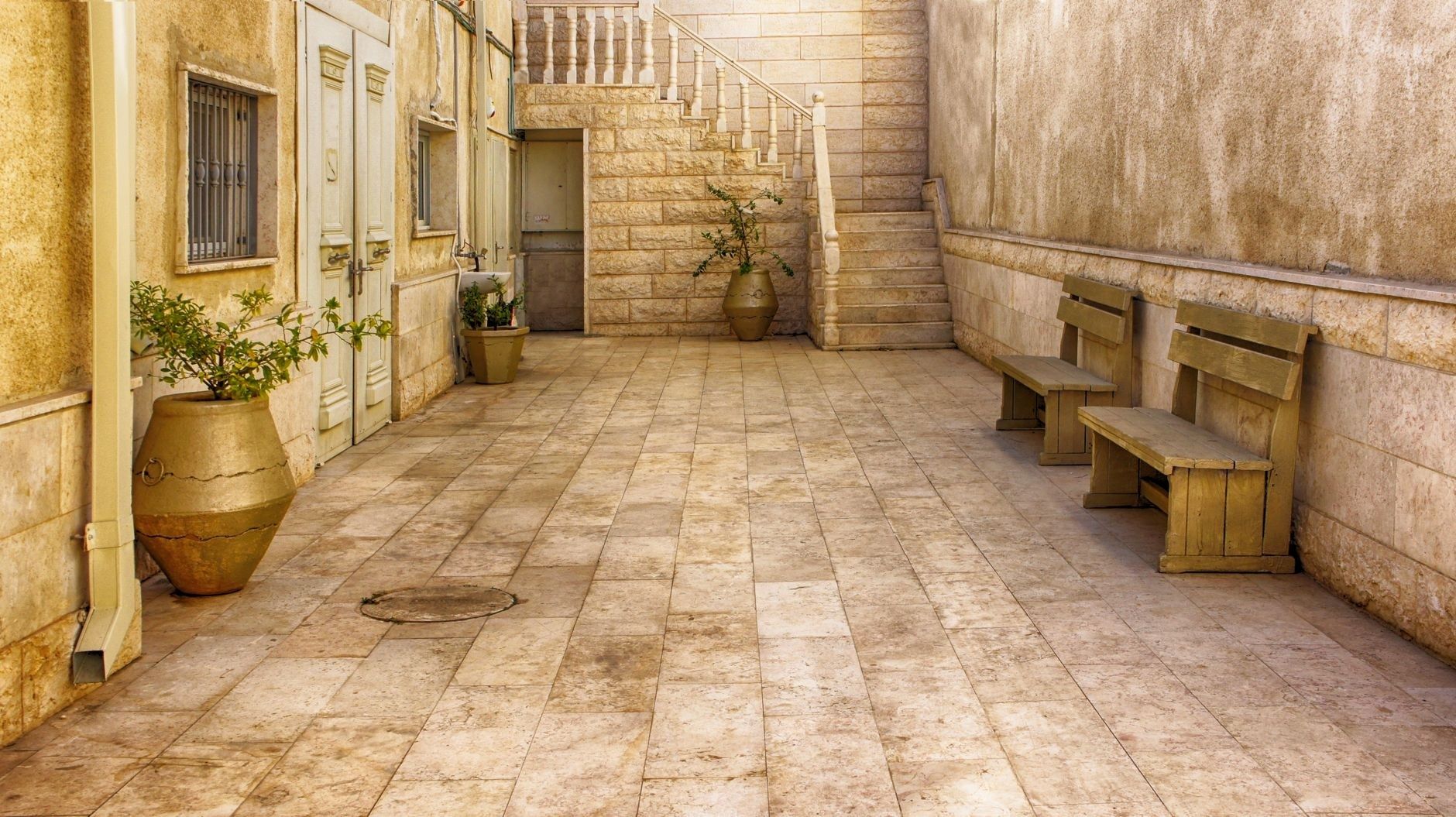 Stone-tiled courtyard with benches, potted plants, and stairs